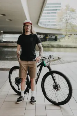 Radfahrer lehnt an seinem Fahrrad während eines Lifestyle-Portraitshootings