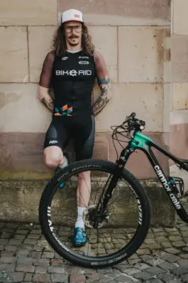 Radfahrer lehnt an seinem Fahrrad während eines Lifestyle-Portraitshootings